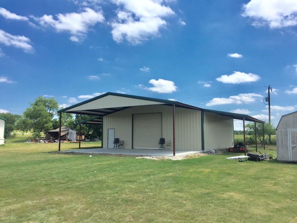 A large metal building is sitting in the middle of a grassy field.