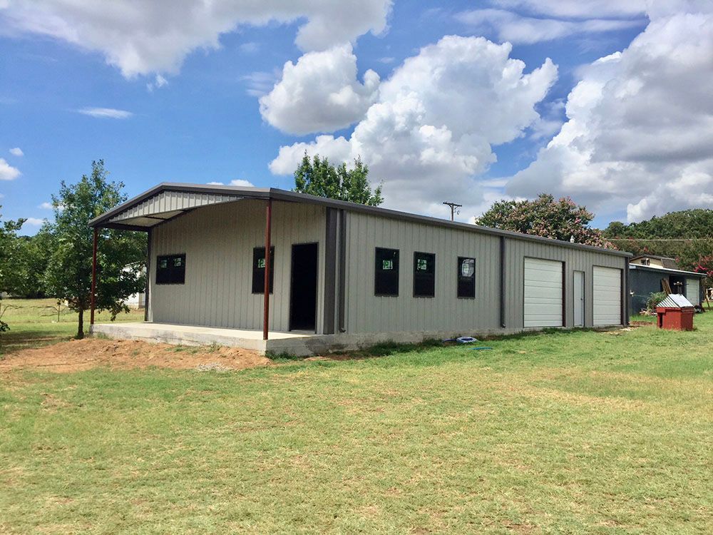 A large metal building is sitting in the middle of a grassy field.