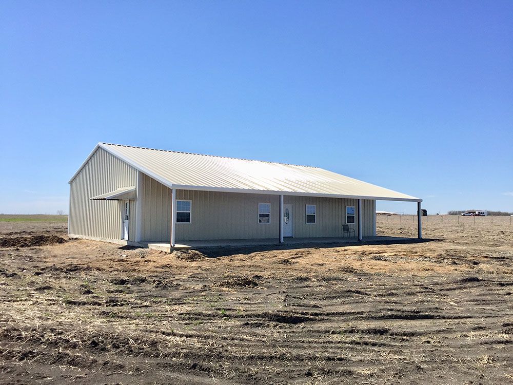 A house is sitting in the middle of a dirt field.