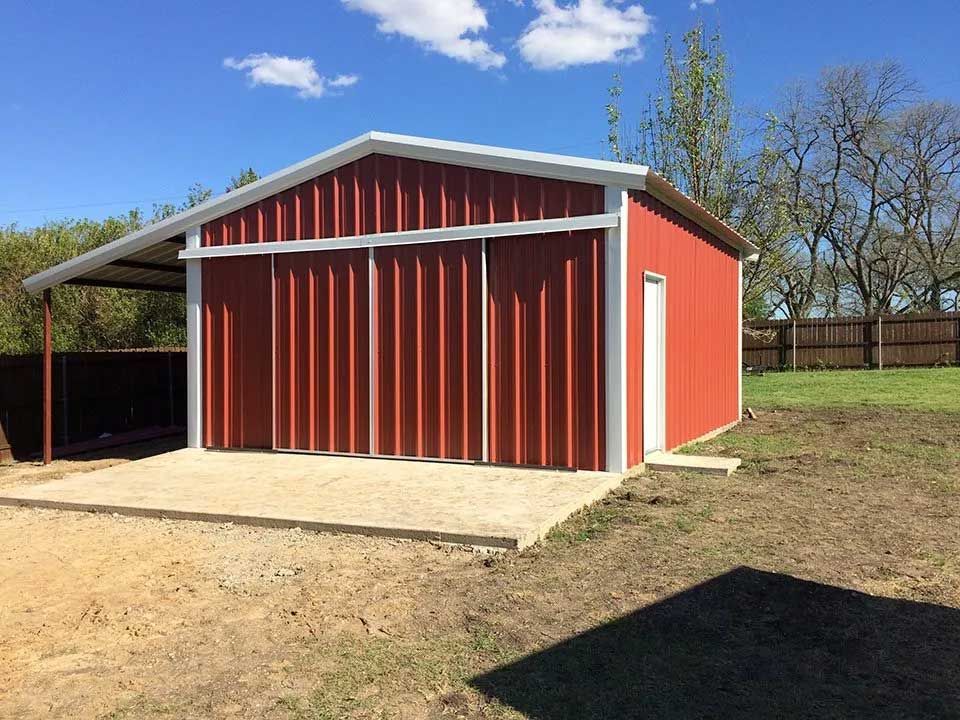 A red barn with sliding doors is sitting in the middle of a field.