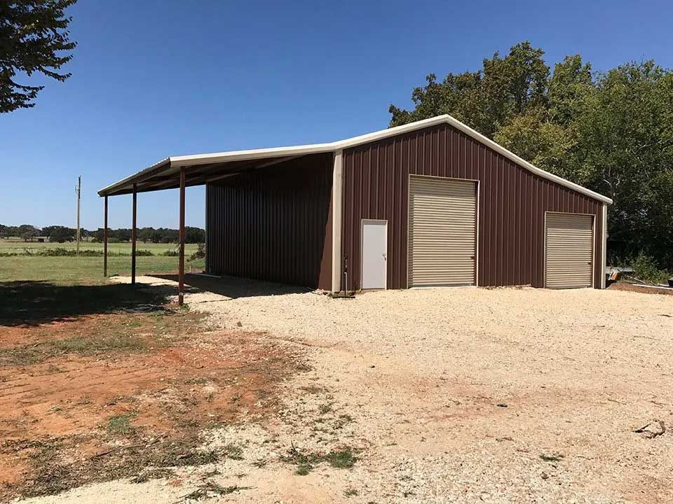 A large brown metal building with two garage doors and a porch.