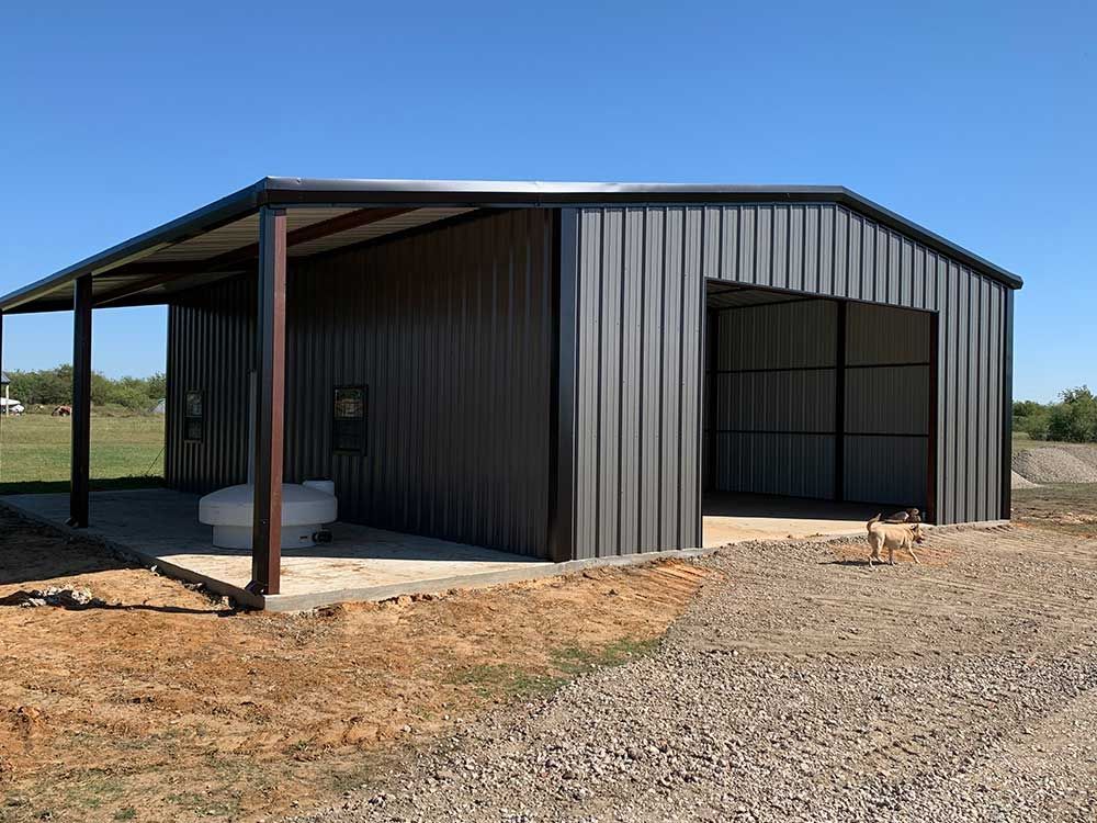 A metal building with a porch and a toilet in the middle of a dirt field.