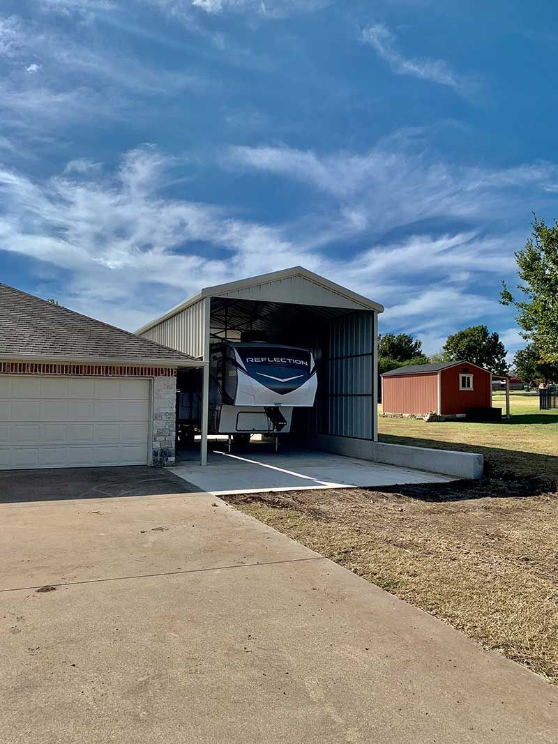 A trailer is parked in a garage next to a house.