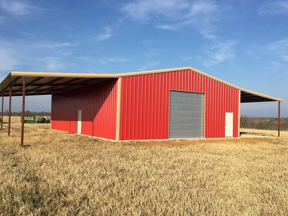 A red building with a roof is in the middle of a field.