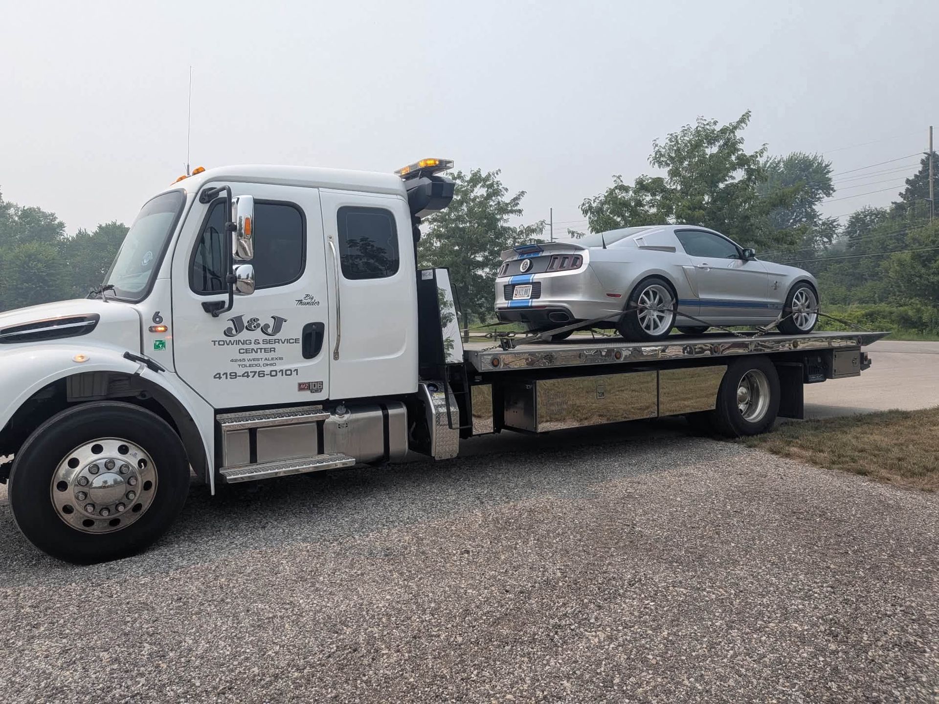 Tow truck carrying a silver sports car