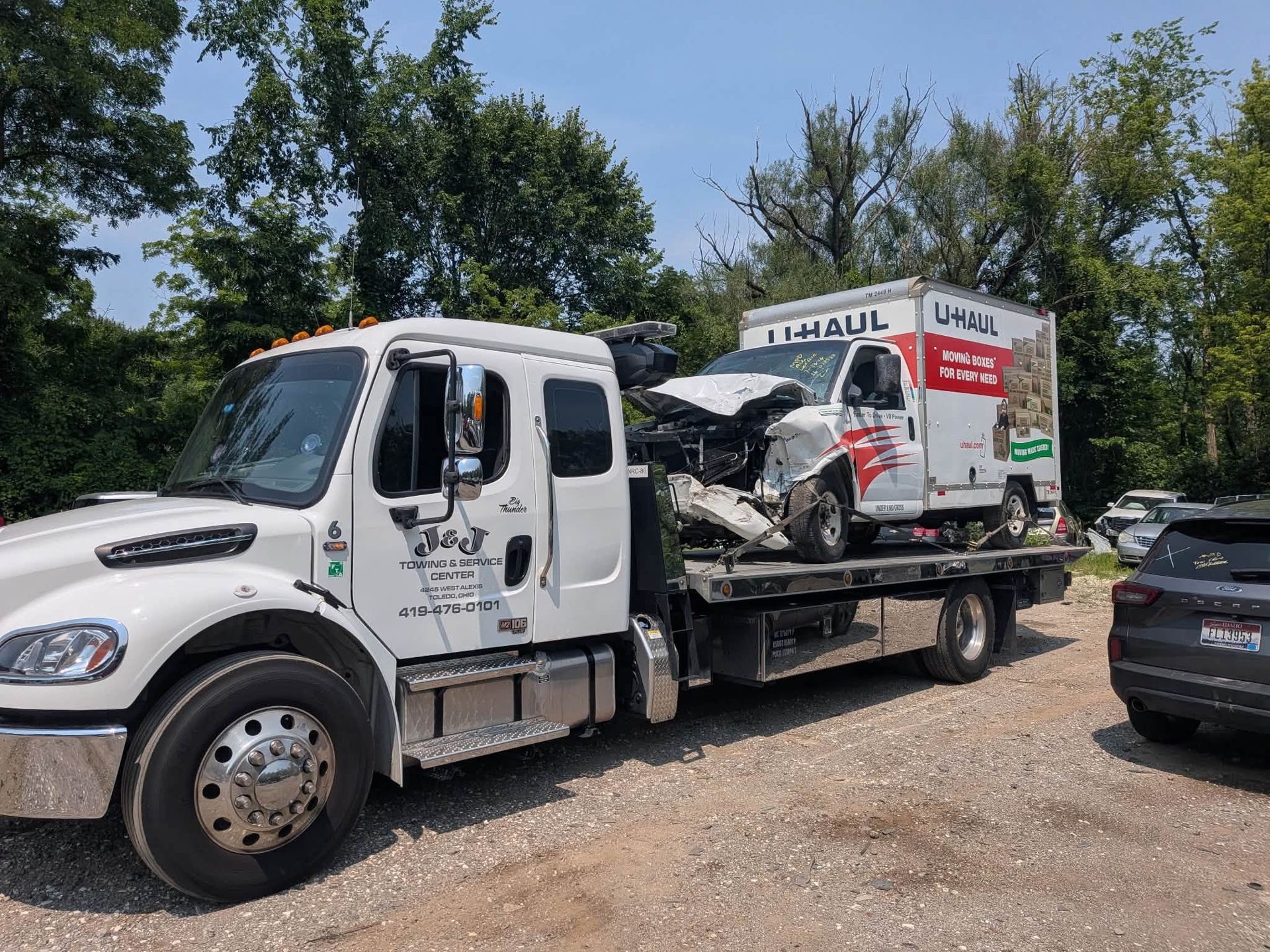 White tow truck carrying a broken-down car
