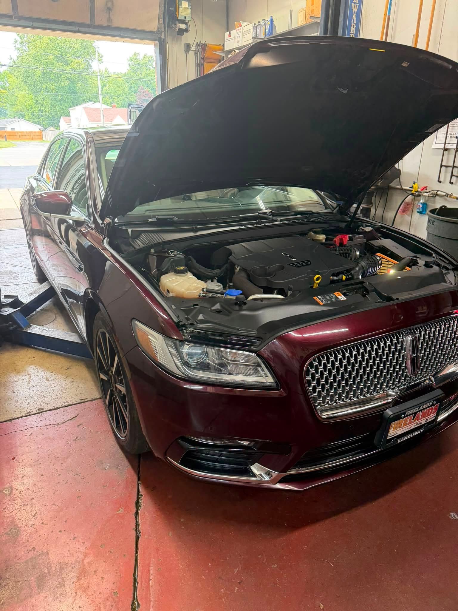 Maroon SUV in a garage with hood open