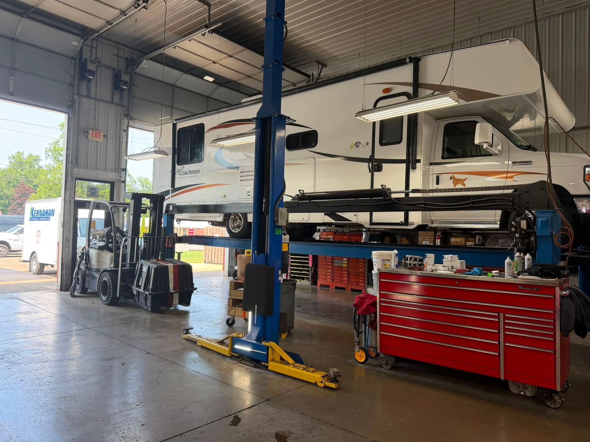 Auto repair shop with a lifted white RV