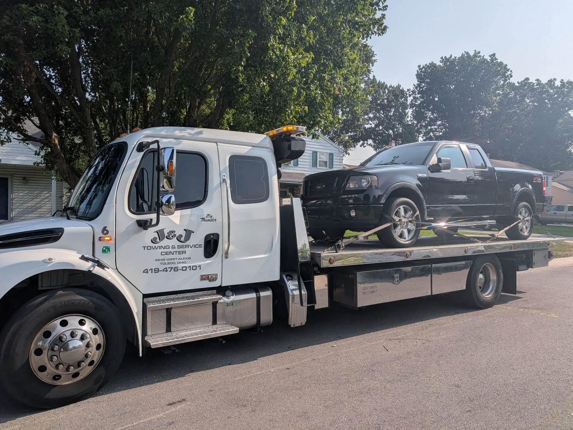 Tow truck carrying a black car on a flatbed trailer