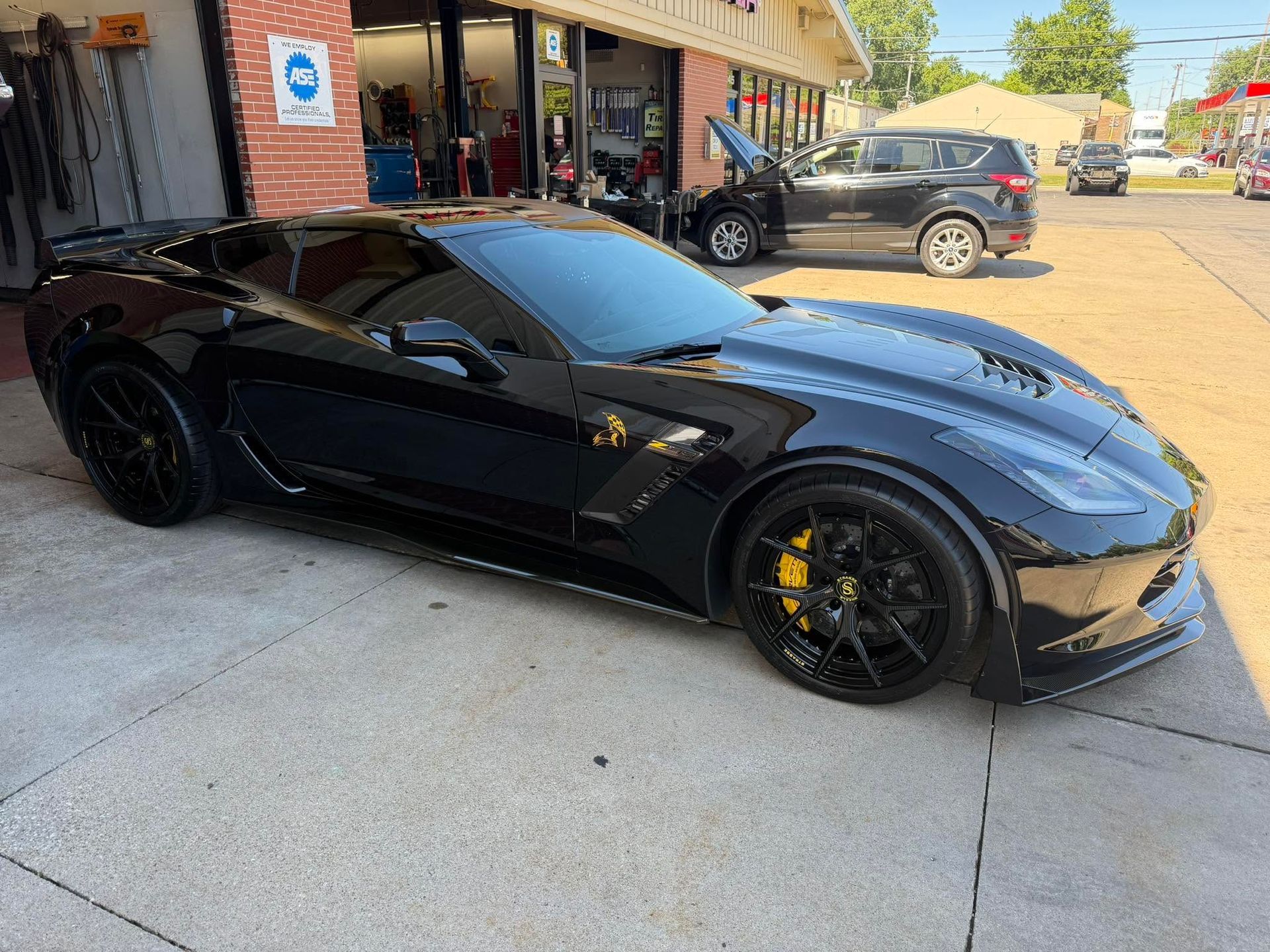 Black sports car parked outside a storefront on a sunny street