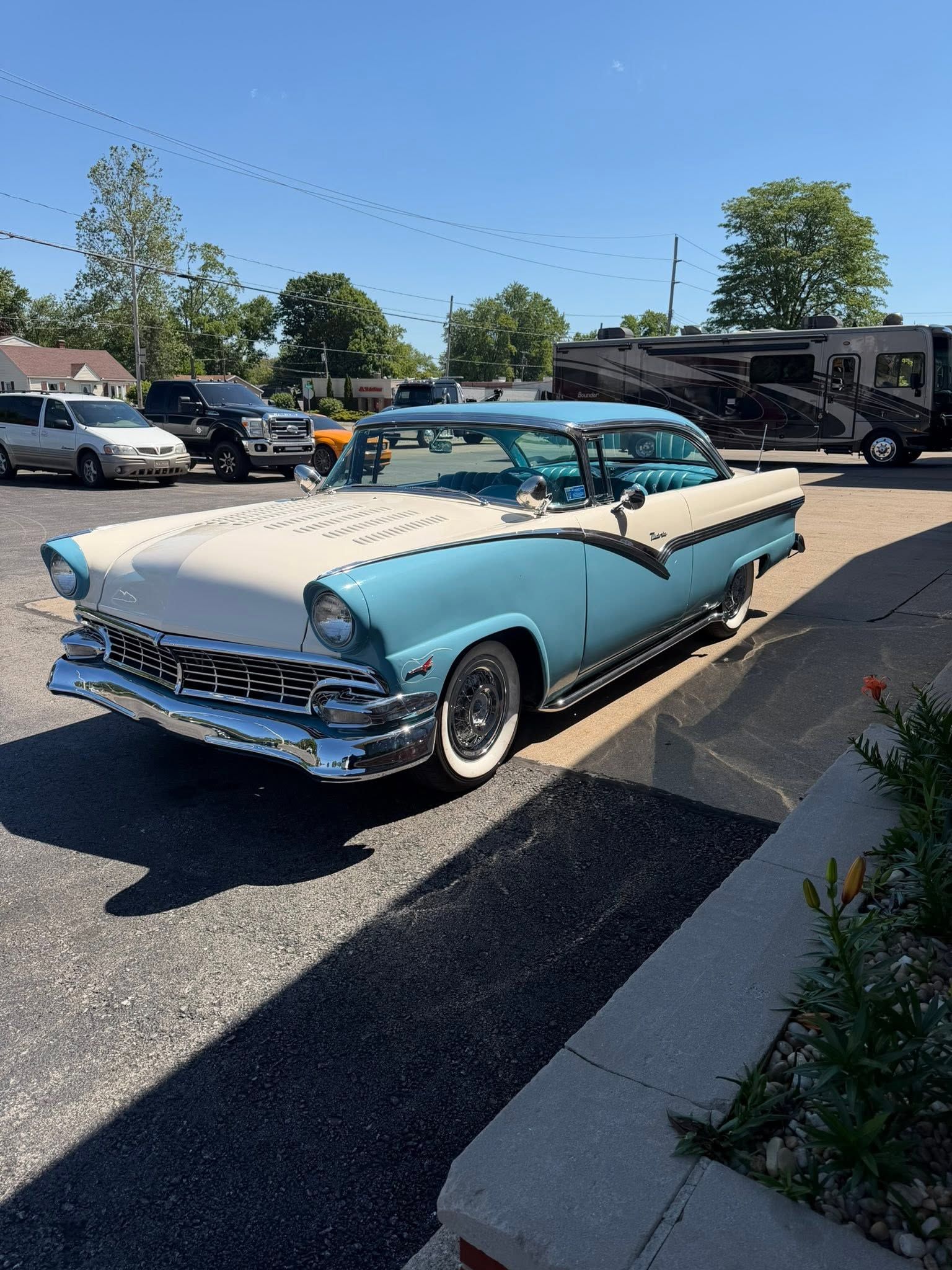 Vintage blue-and-white convertible car parked outdoors in a sunny lot