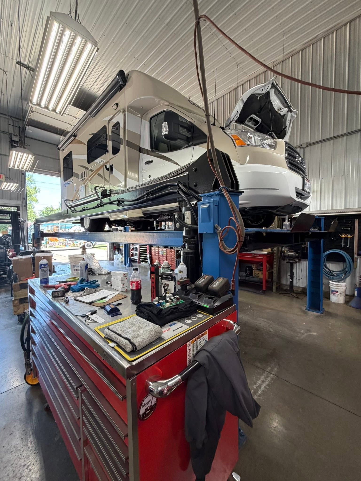 White boat on a lift in a repair shop, with tools and a red rolling toolbox in the foreground