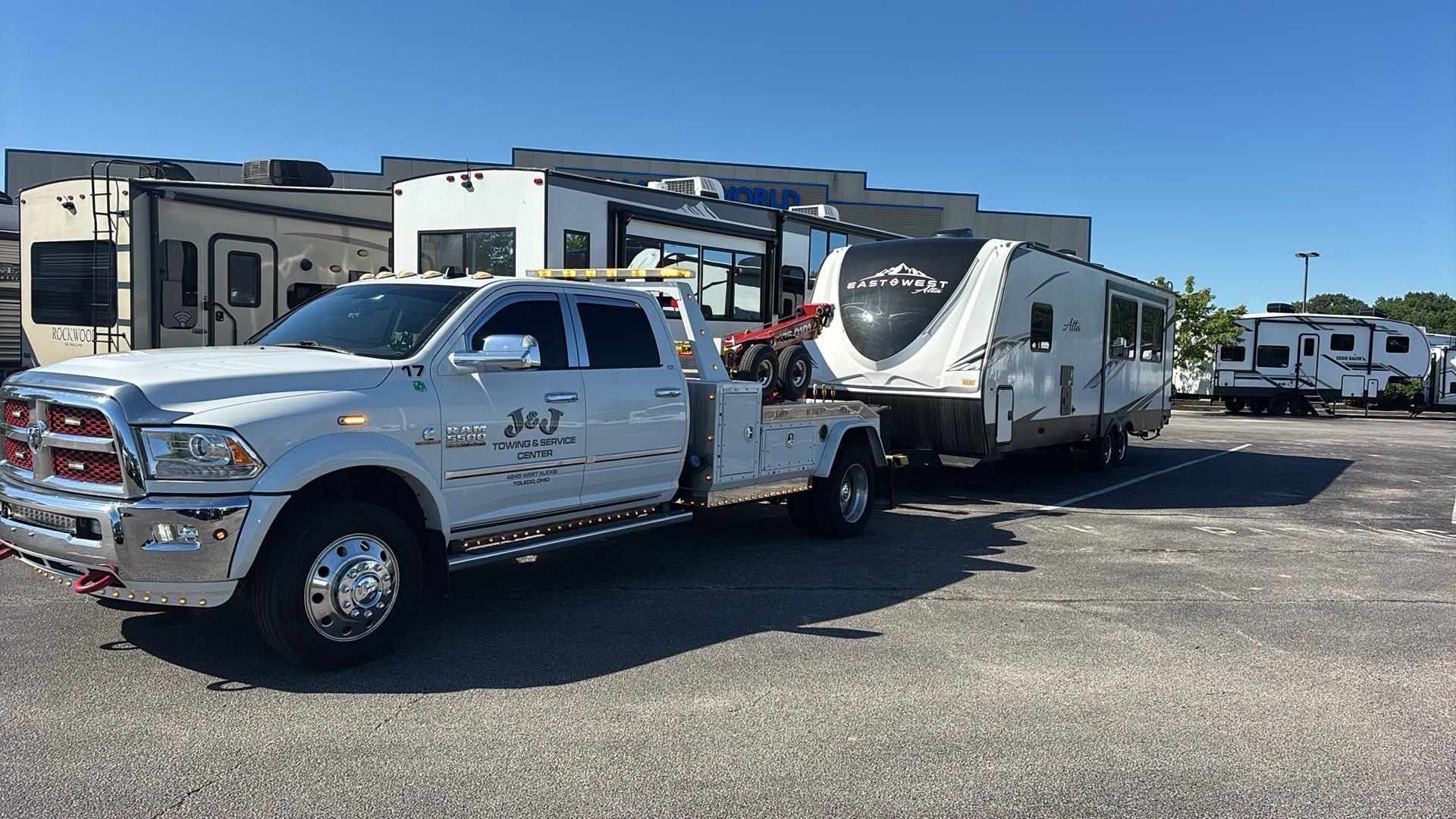 Chrome pickup truck towing a white RV trailer in a gravel lot under a clear blue sky