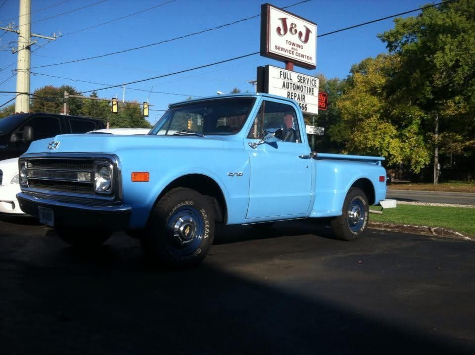 Light blue vintage Chevrolet pickup truck parked outside of a business with a sign.