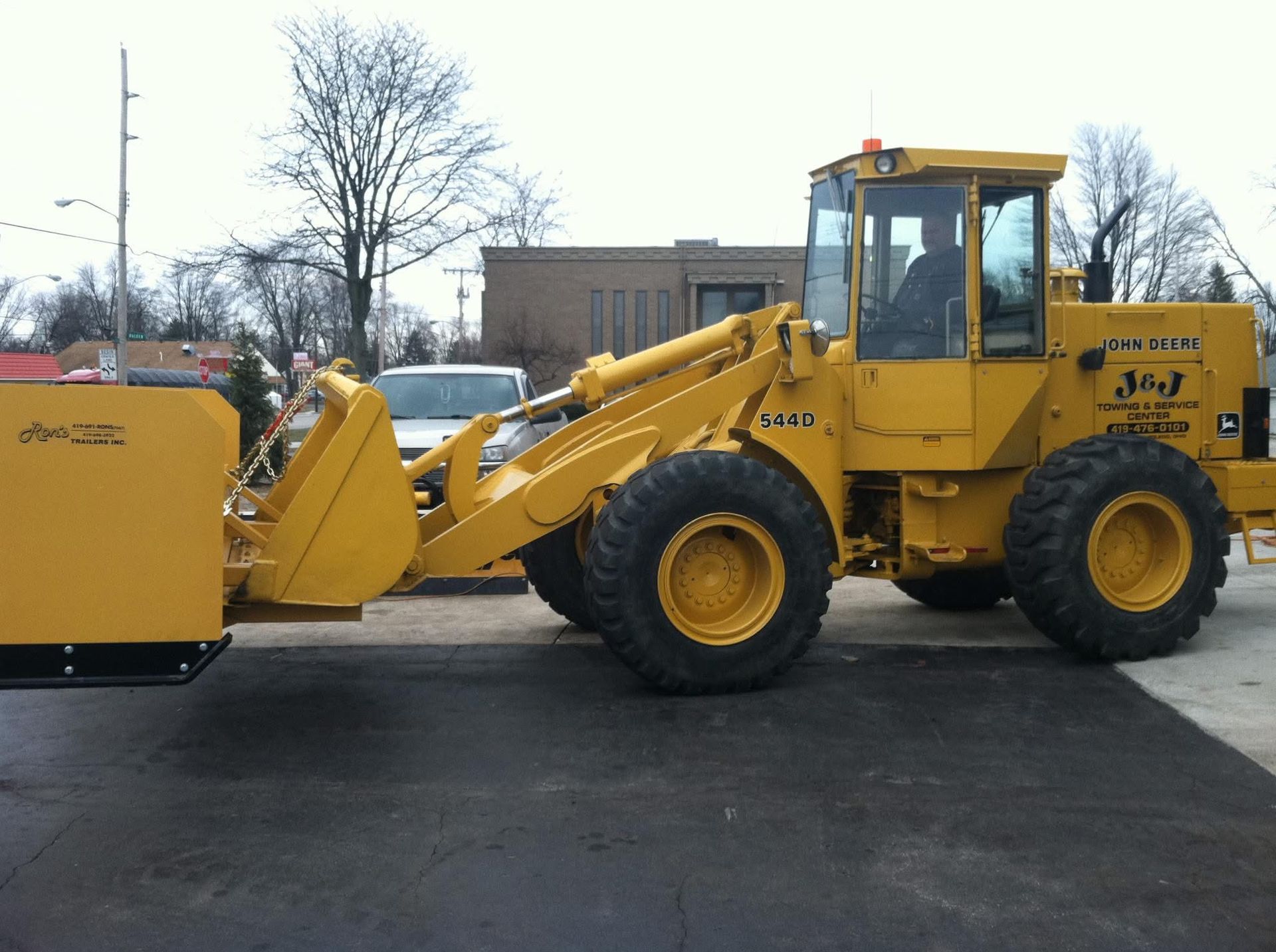 Yellow J-3 wheel loader plowing pavement; operator in cab.