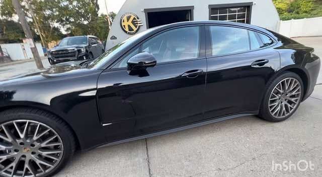 A black Porsche sedan was parked outside a building.