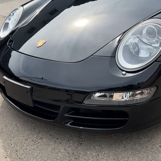 Black Porsche sports car front view, hood and bumper visible.