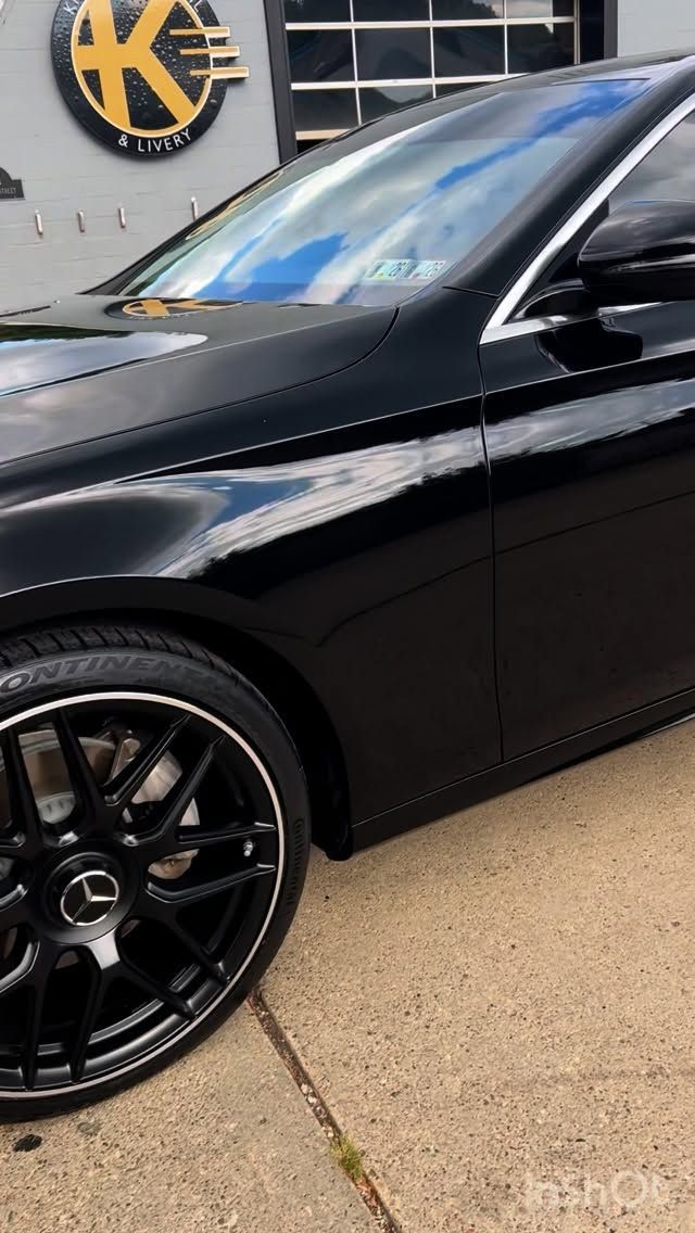 Black Mercedes-Benz sedan parked in front of a building with a “K” logo.