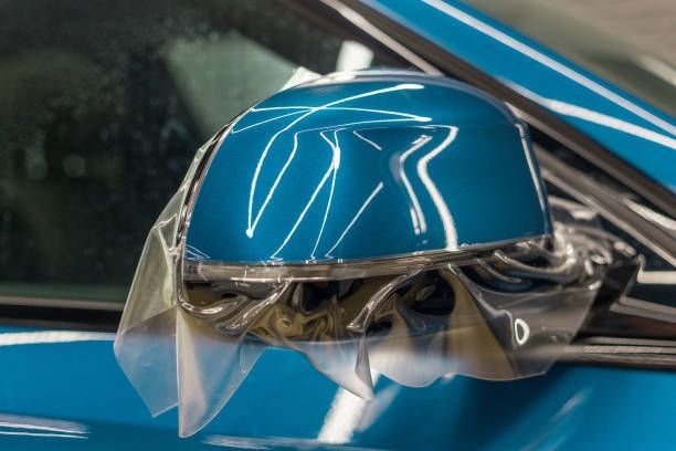 Blue car side mirror wrapped in clear protective film.