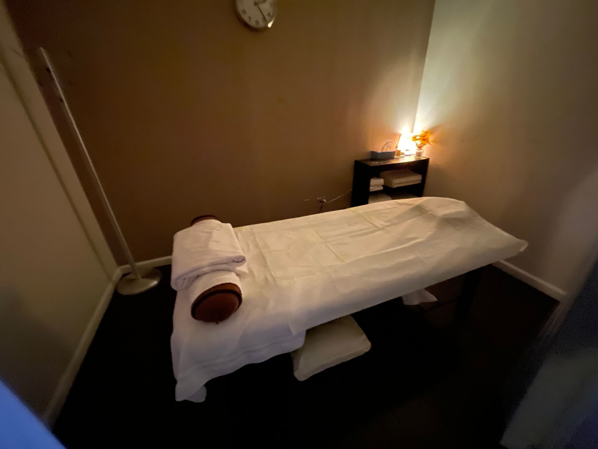 Massage room with massage table, towels, and small shelf.