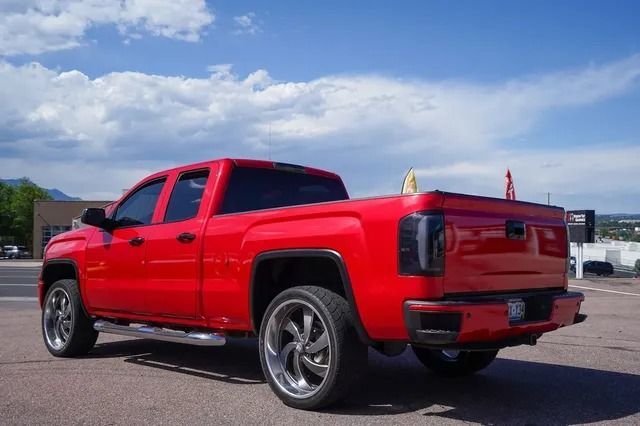Red lifted pickup truck parked on a lot under a blue sky
