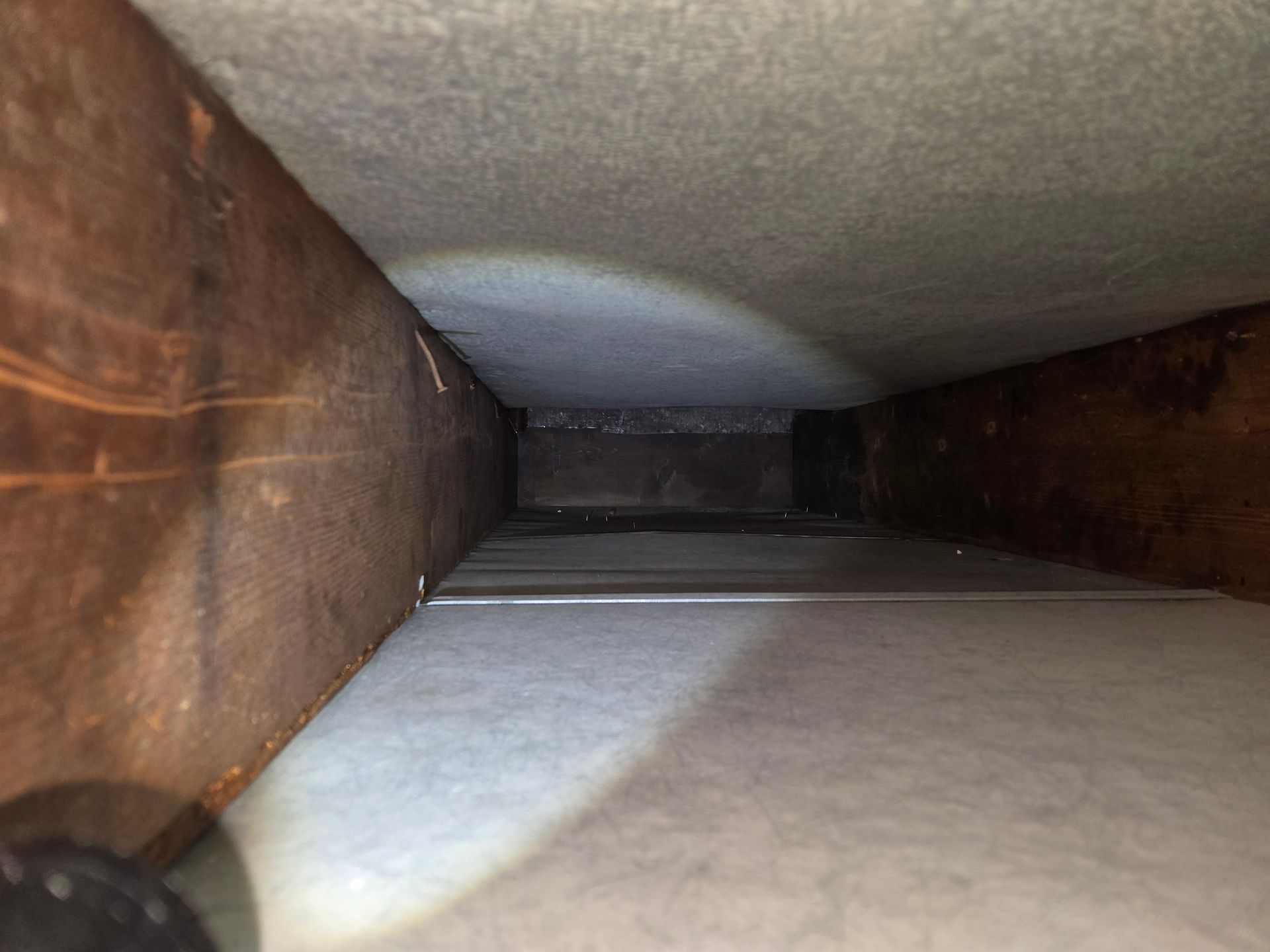 Interior view of an air duct. Gray, rectangular with some staining at the edges.