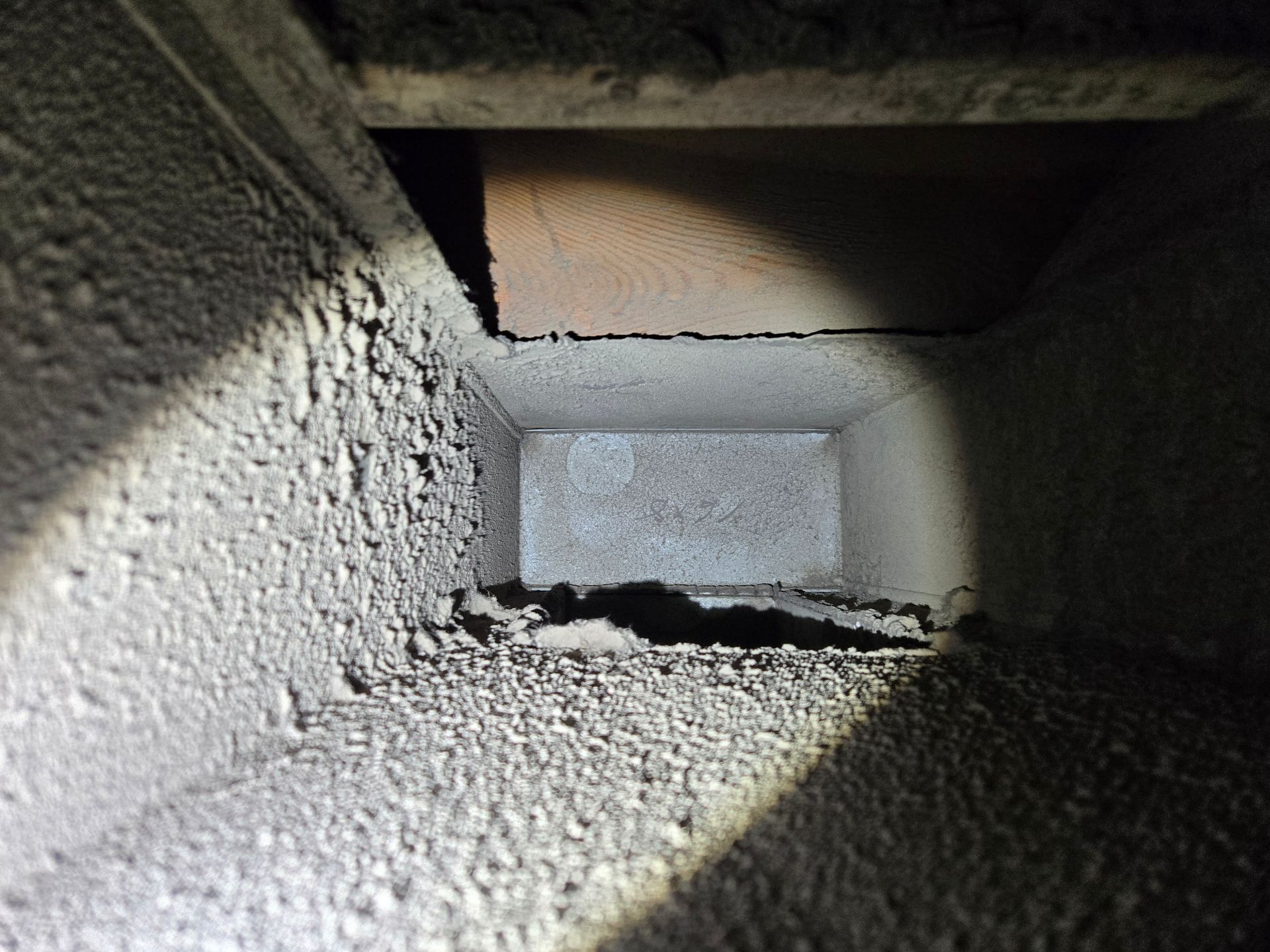 Inside of a dusty rectangular chimney, leading to a dark opening above.