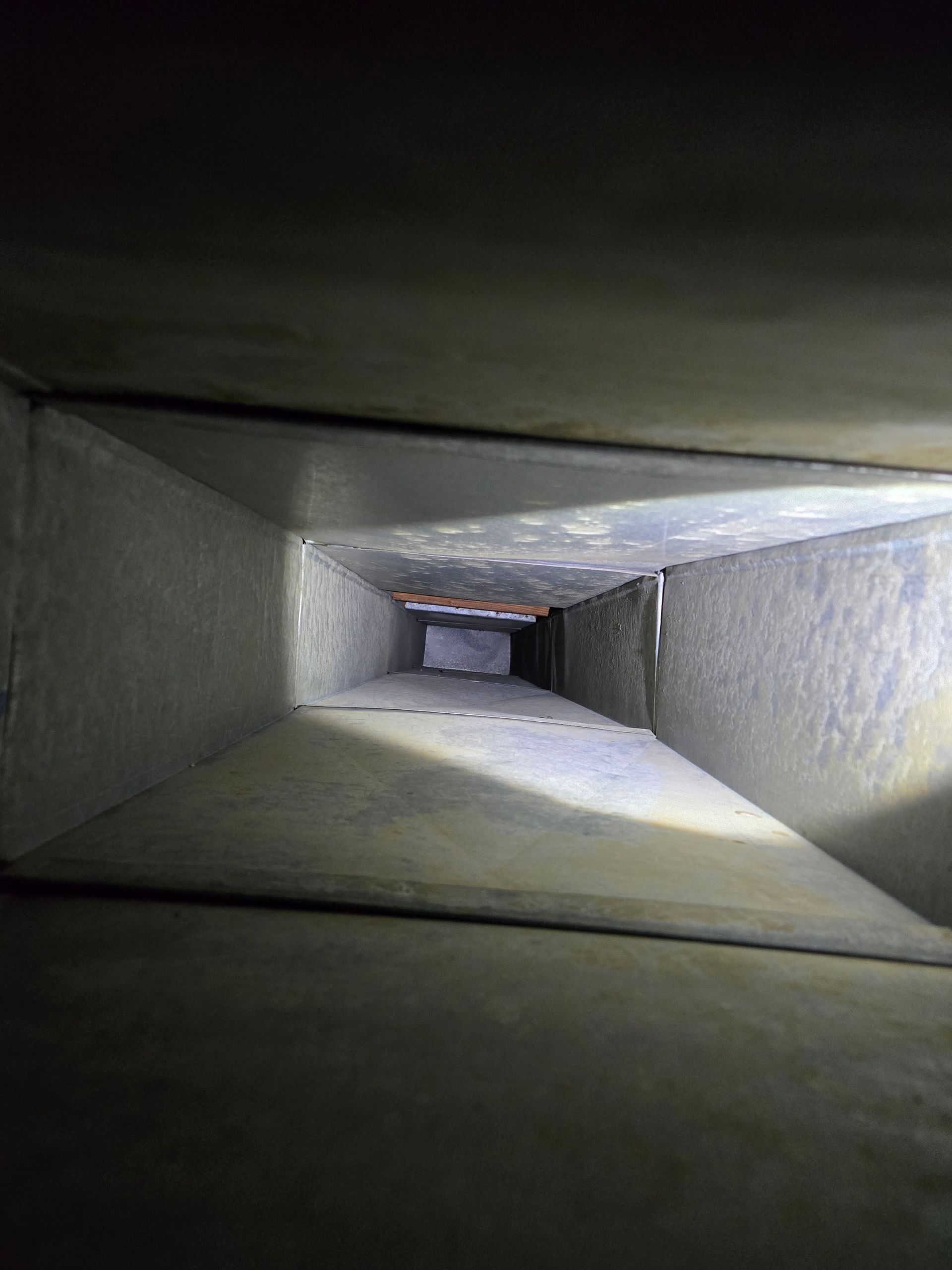 Inside view of a rectangular air duct, gray metal walls, vanishing point perspective.