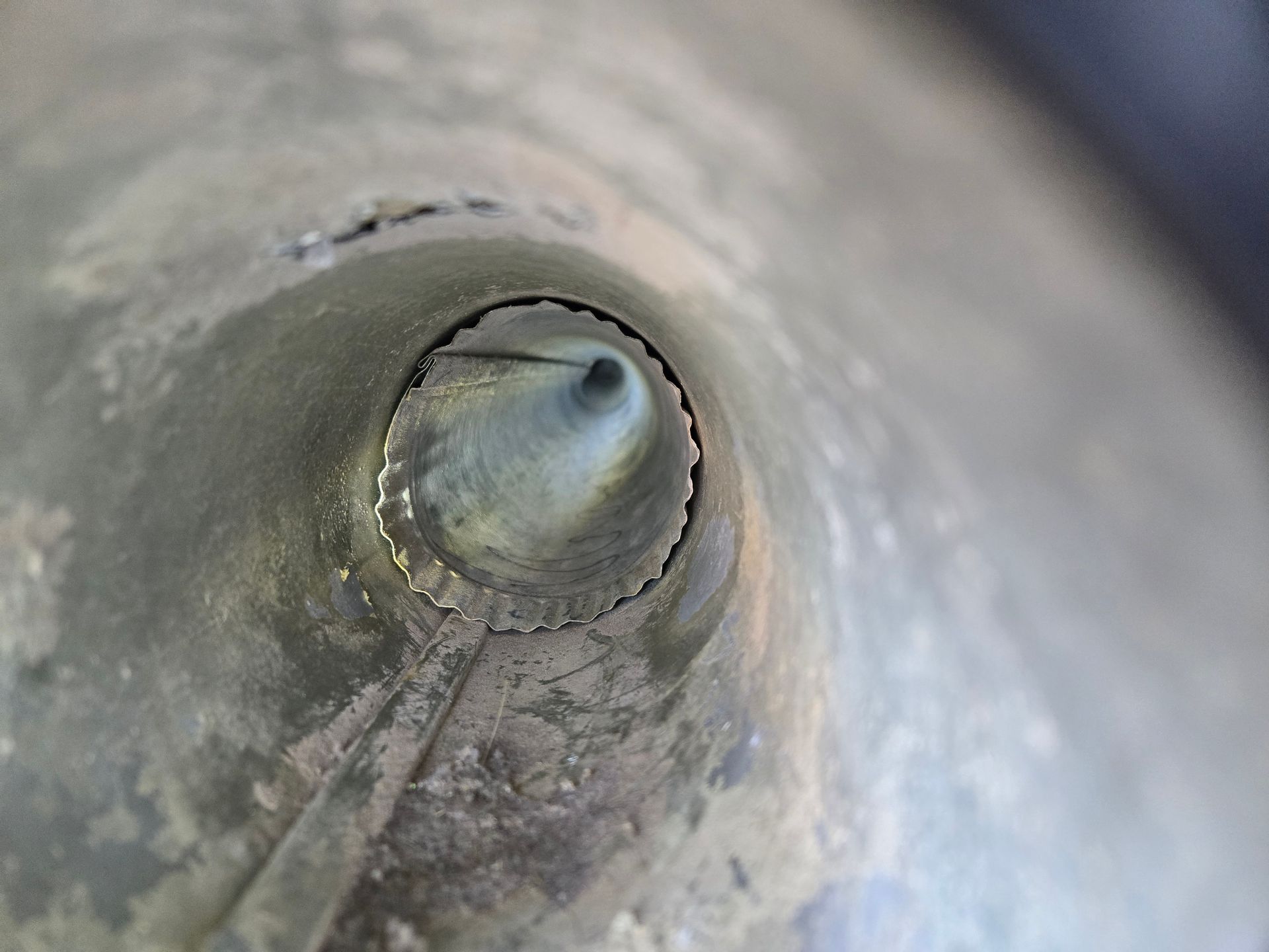 Looking down a metallic tube, light at the end, possible pipe.