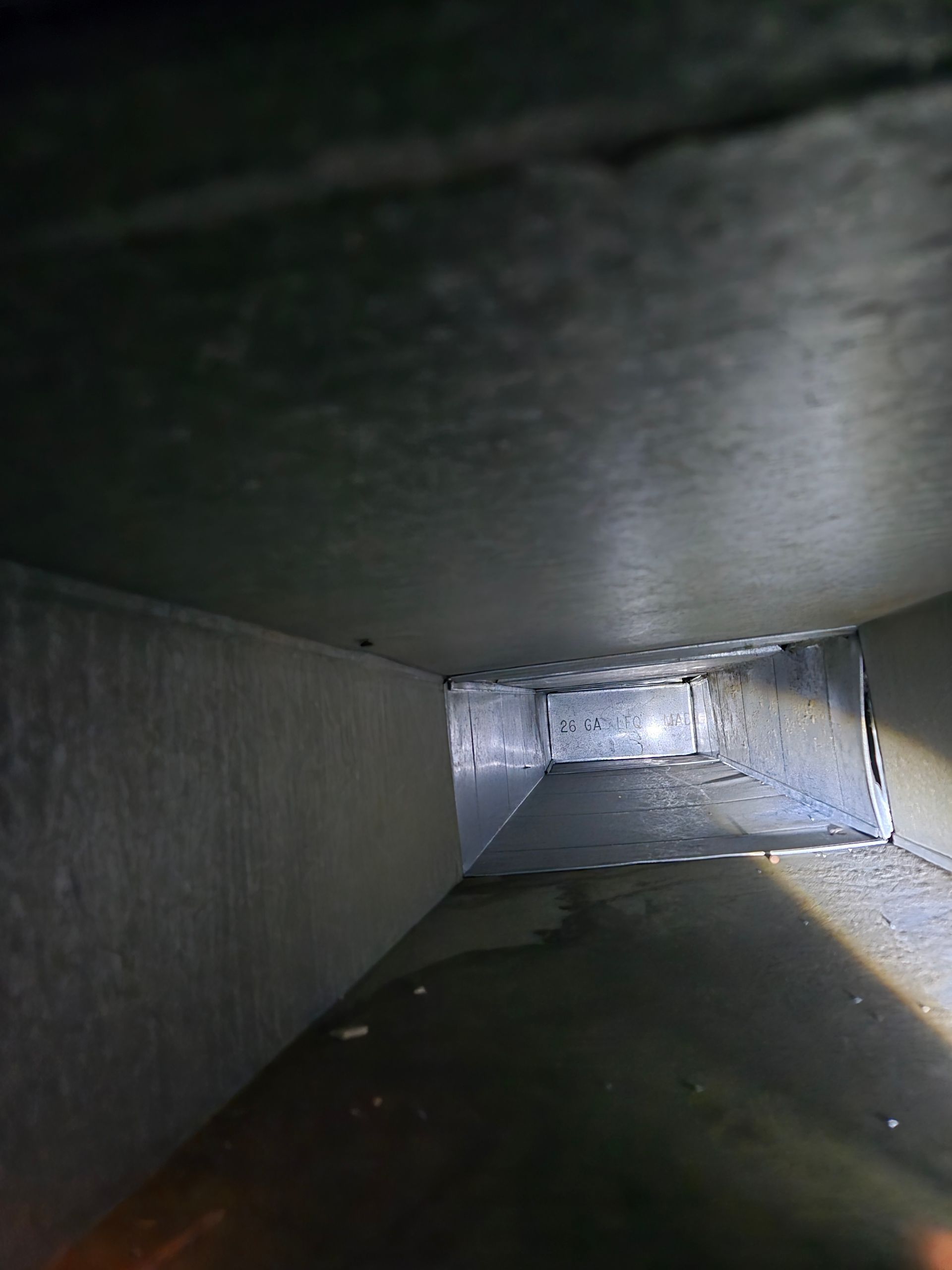 Interior of a rectangular metal duct. The walls appear to be dusty.