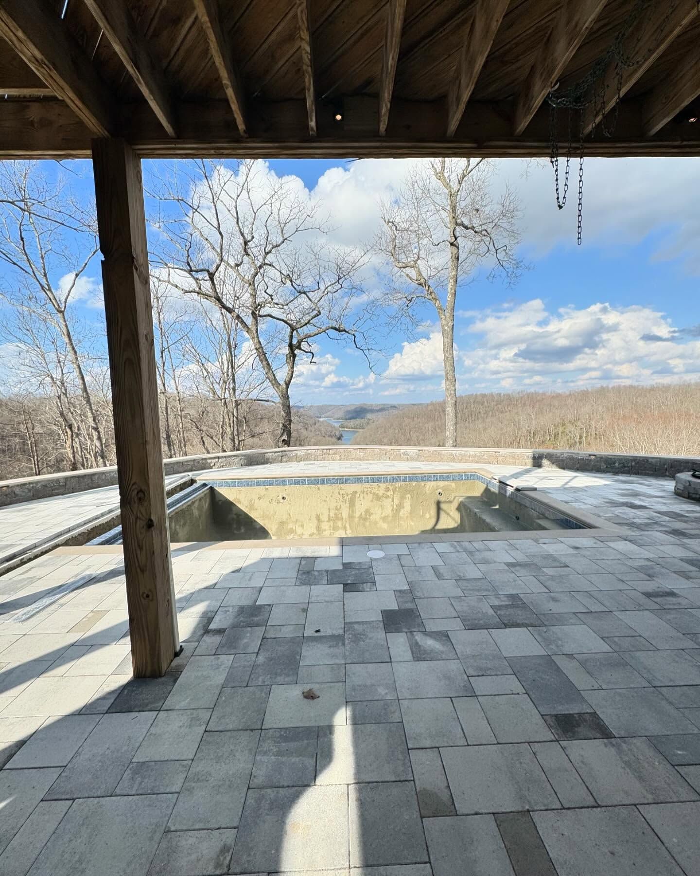 Covered patio with stone pavers overlooking a winter field and bare trees under a blue sky