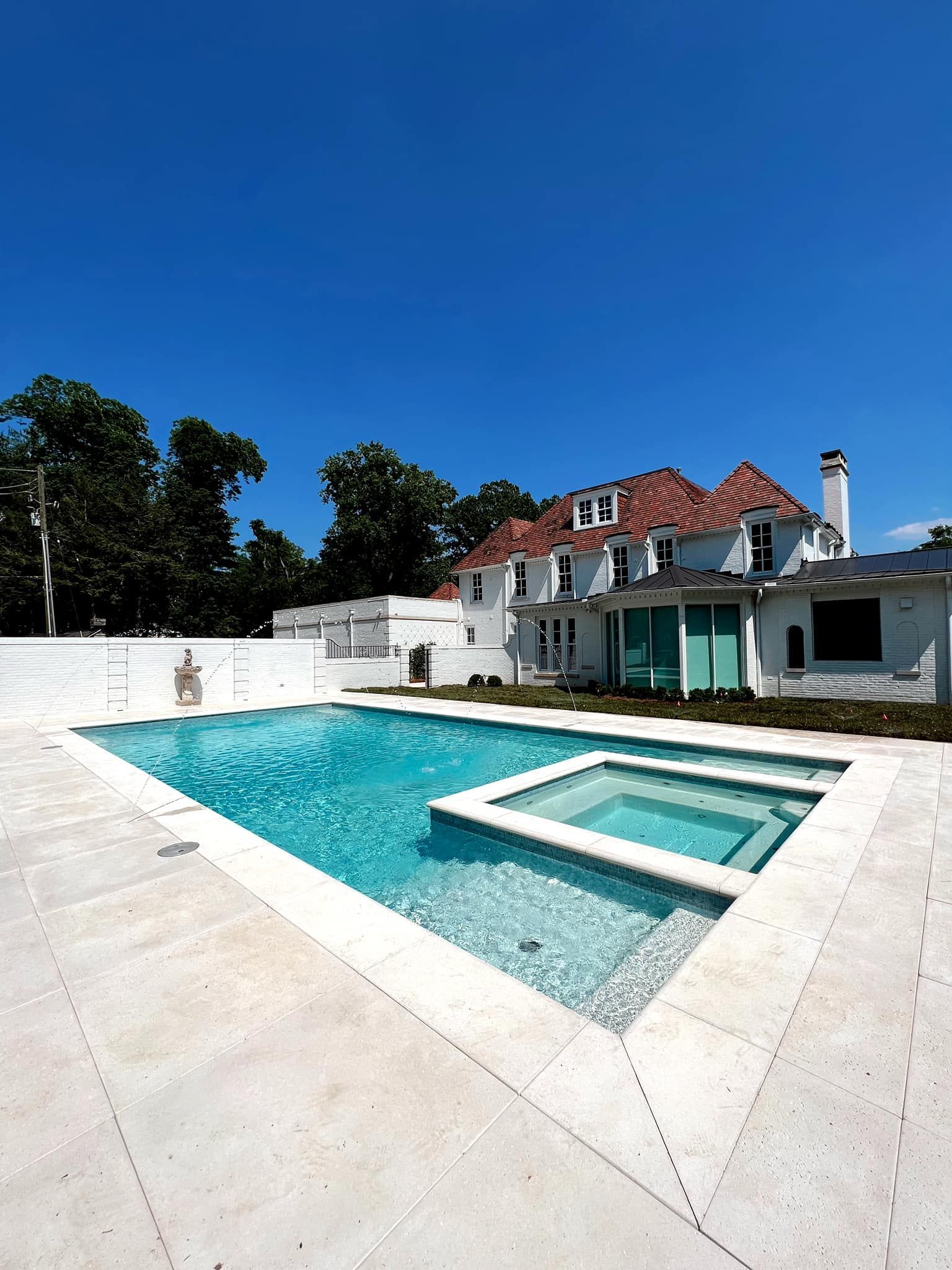 Modern white villa with a turquoise swimming pool under a clear blue sky
