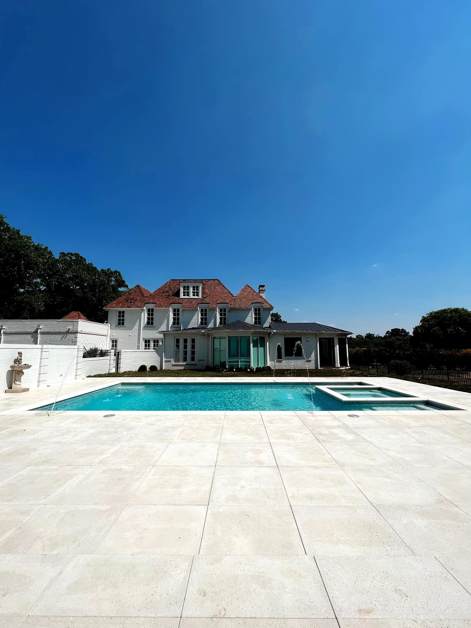White villa with red roof beside a turquoise pool under a clear blue sky