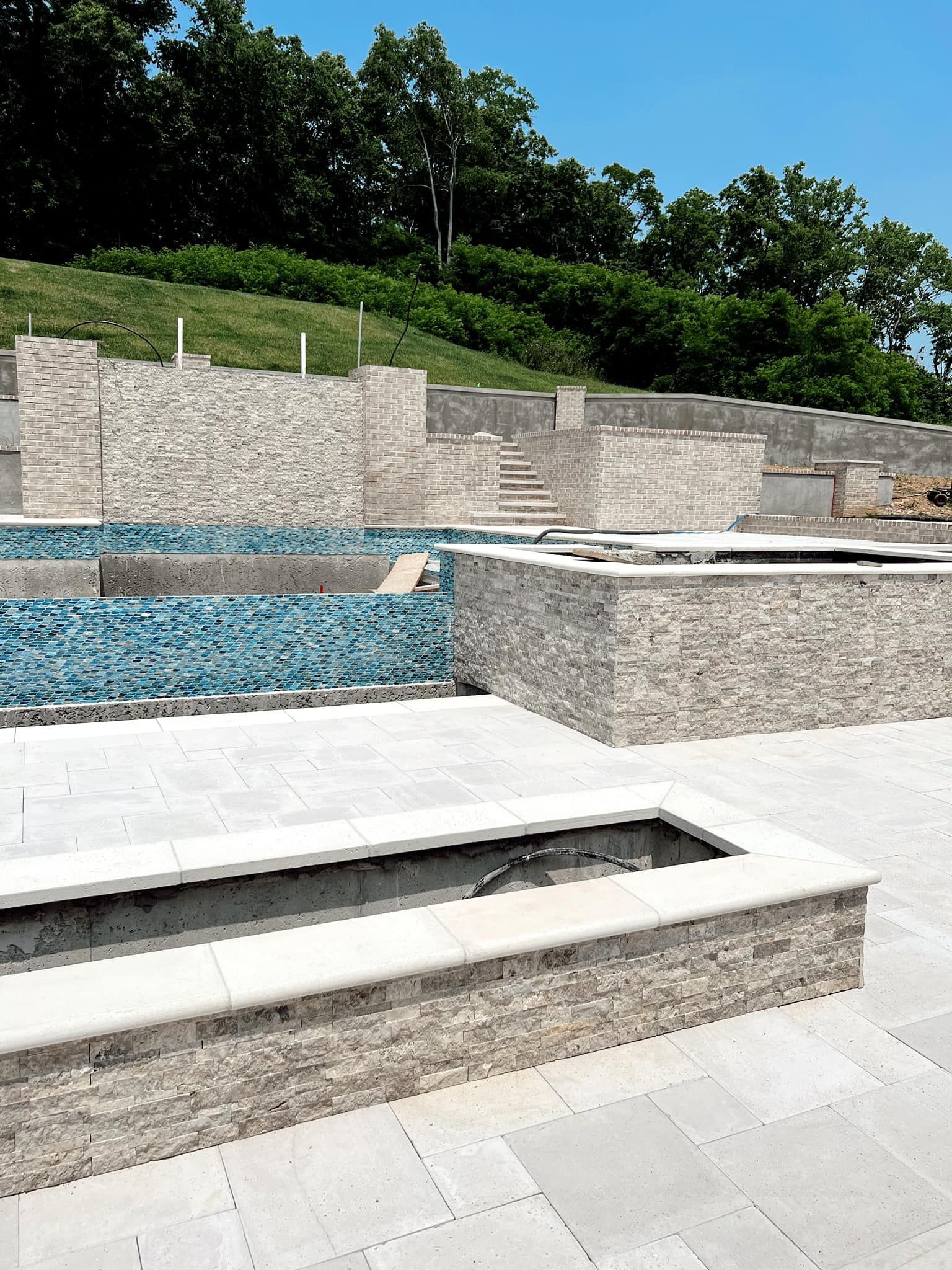 Modern stone terrace with shallow blue pools and steps on a sunny hillside