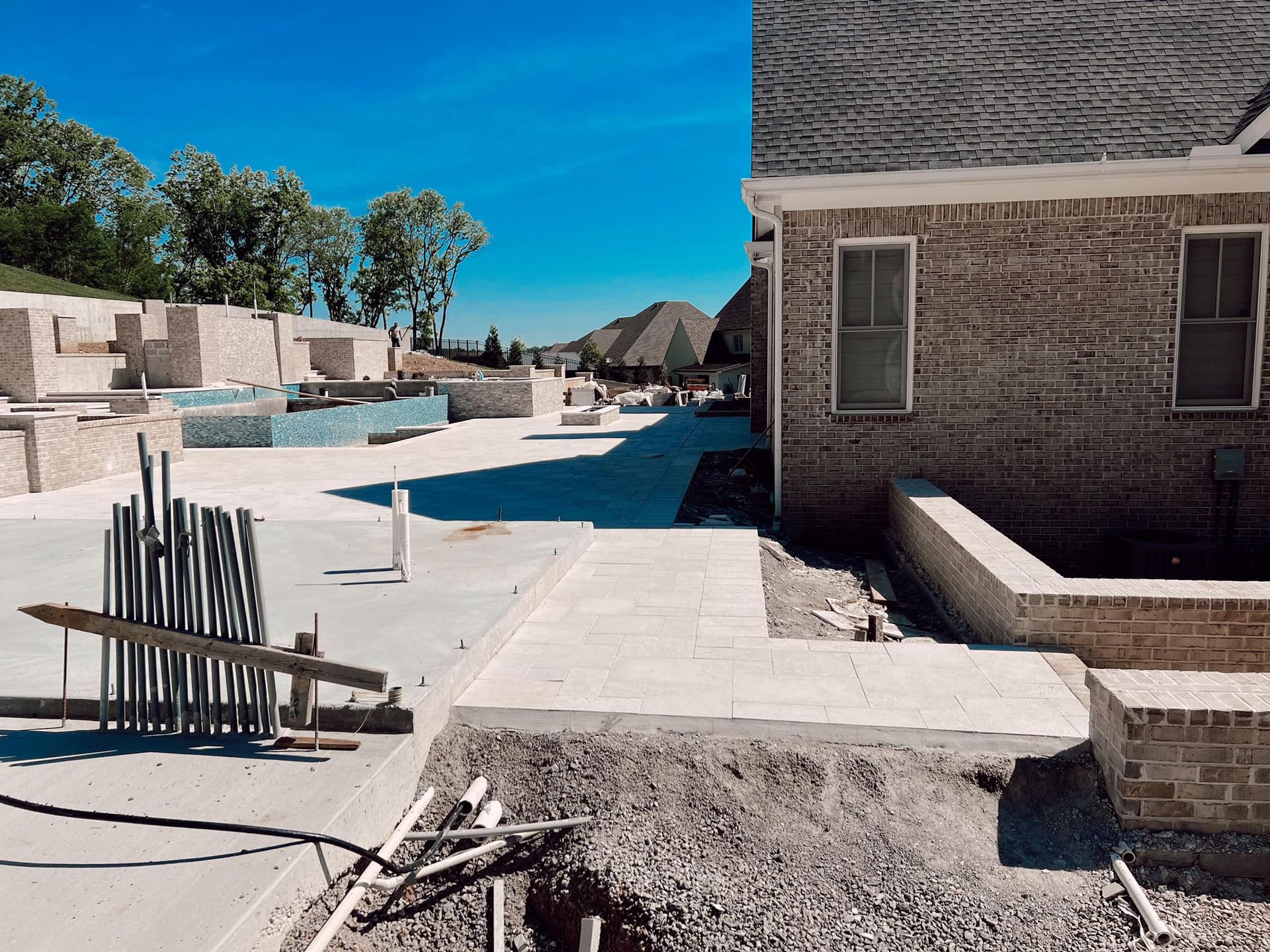 Desert resort pool area with empty lounge chairs, white walkways, and brick buildings under a bright blue sky