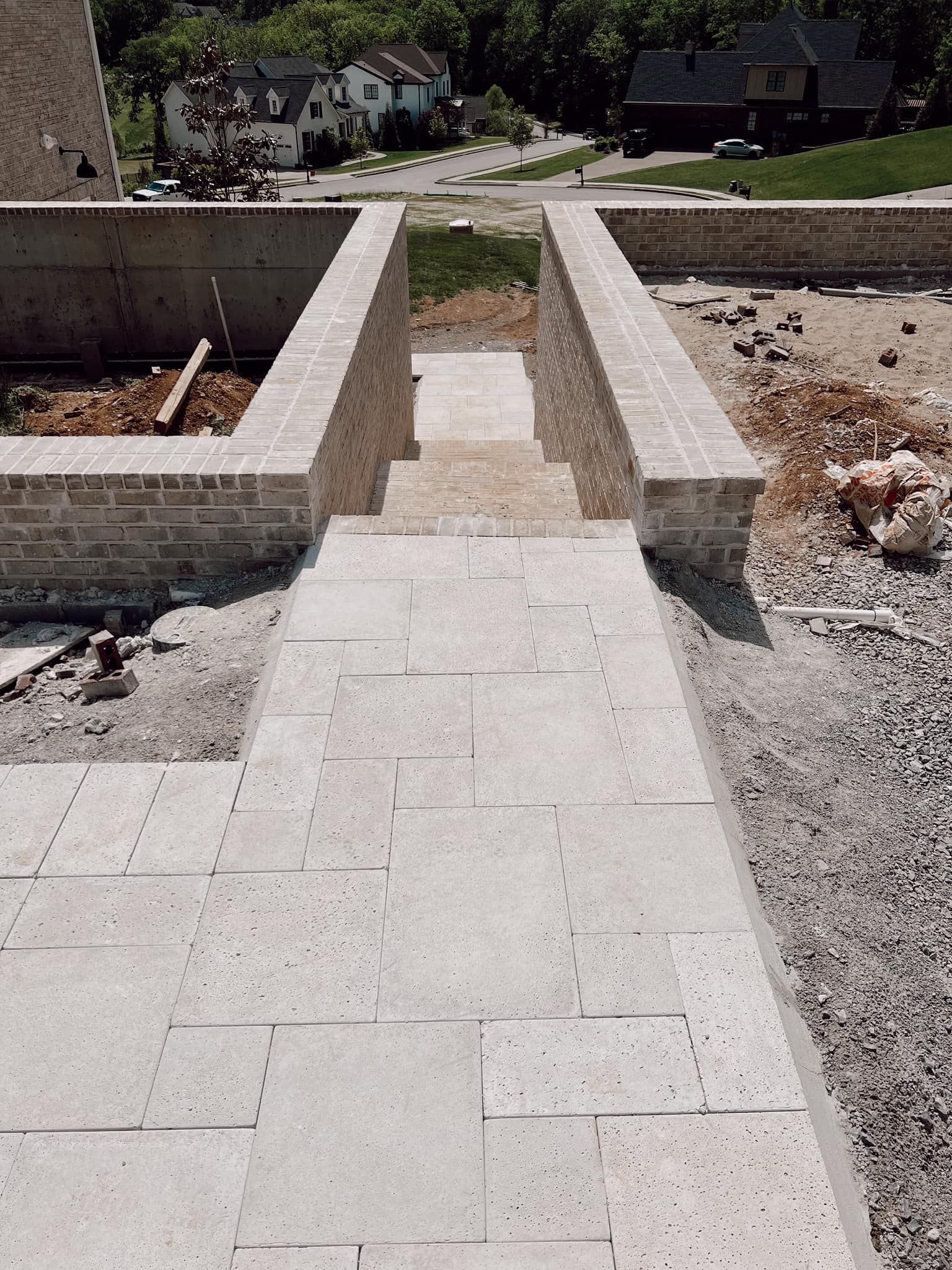 Stone walkway leading to steps between low walls in a gravel and dirt residential construction area