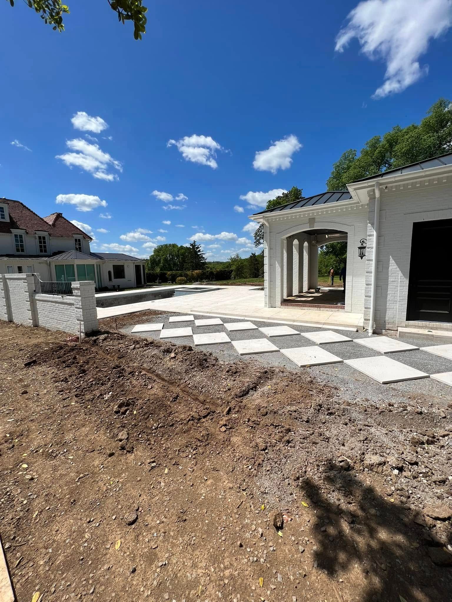 Partially built white house with checkered patio under a bright blue sky
