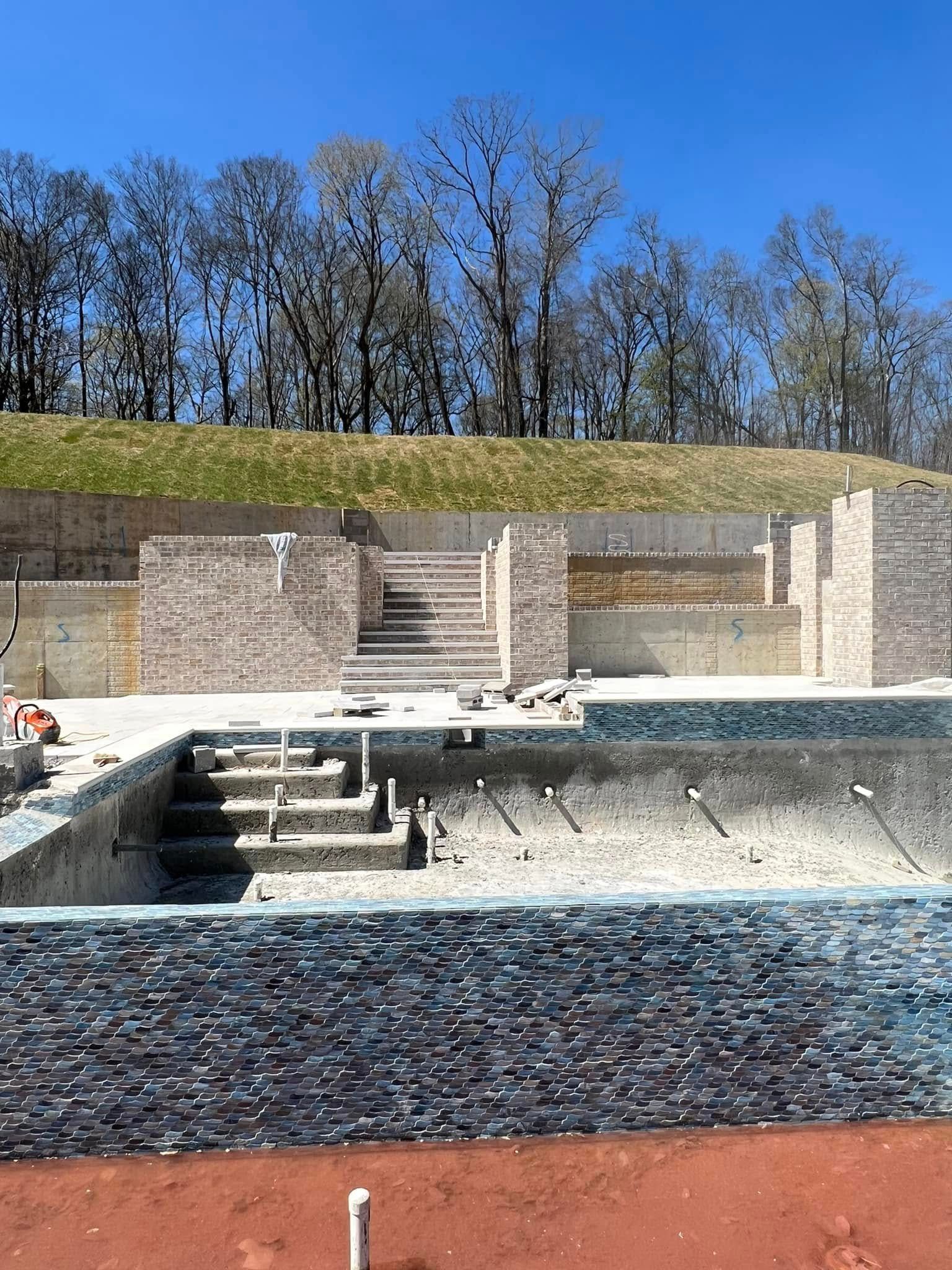 Empty outdoor amphitheater with stone seating, steps, and a blue sky above leafless trees