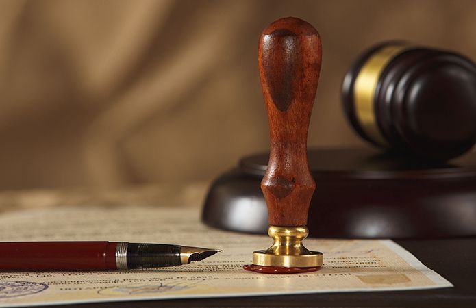 A wooden stamp is sitting on top of a piece of paper next to a pen.