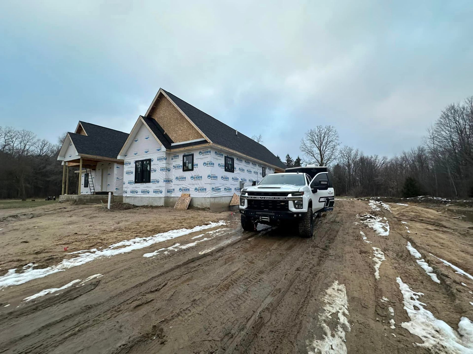 a white truck is parked in front of a house under construction