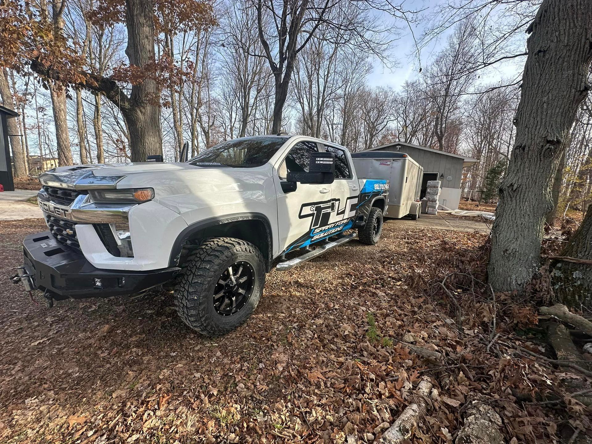 a white truck is parked in the woods next to a tree
