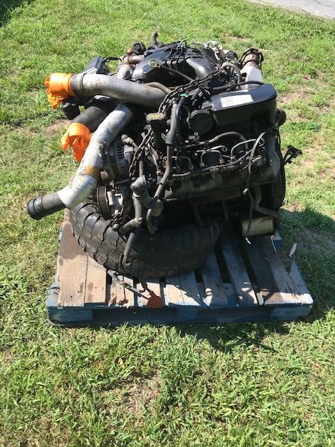 Diesel engine on a pallet, outdoors on grass. Black and silver components.