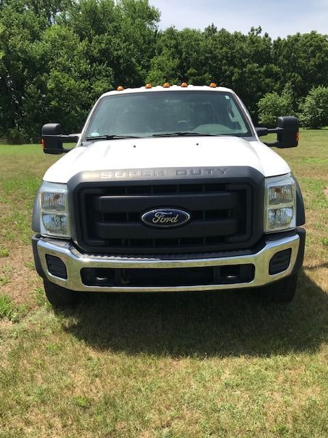 White Ford F-Series Super Duty truck on a grassy lawn with trees in the background.