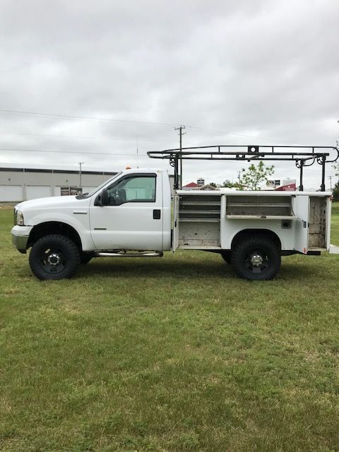 White work truck with utility bed on grass.