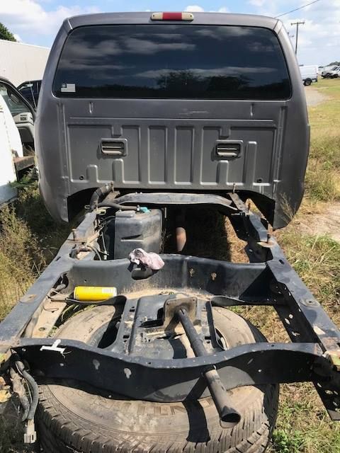 Gray truck cab mounted above a black truck frame with no bed, sitting on tires, outdoors.