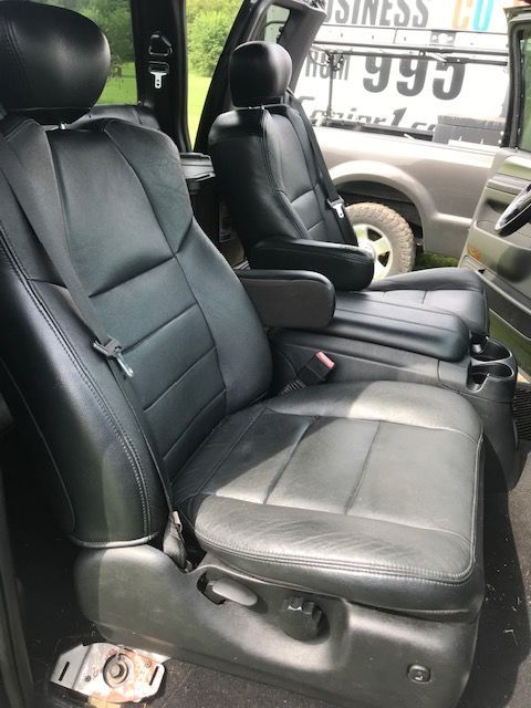 Black leather vehicle seats with armrests, likely in a truck, viewed from the front.