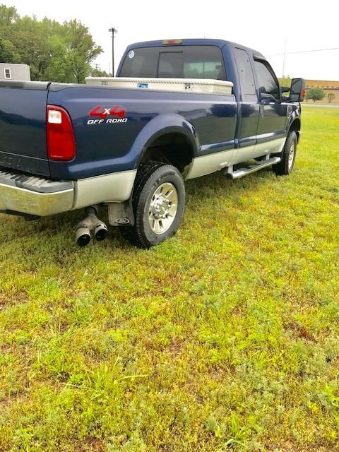 Blue Ford F-350 truck with a silver toolbox, parked on grass. 