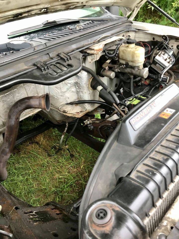 Open truck hood showing engine components, including brake master cylinder and exhaust pipe.
