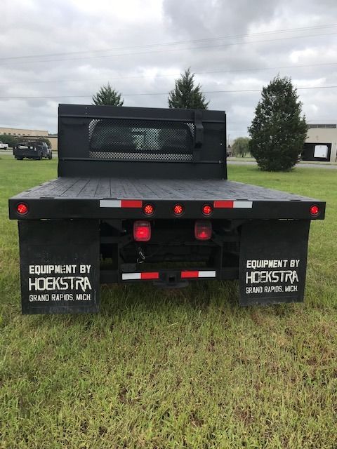 Black flatbed truck with red lights and mud flaps on a grassy lawn.