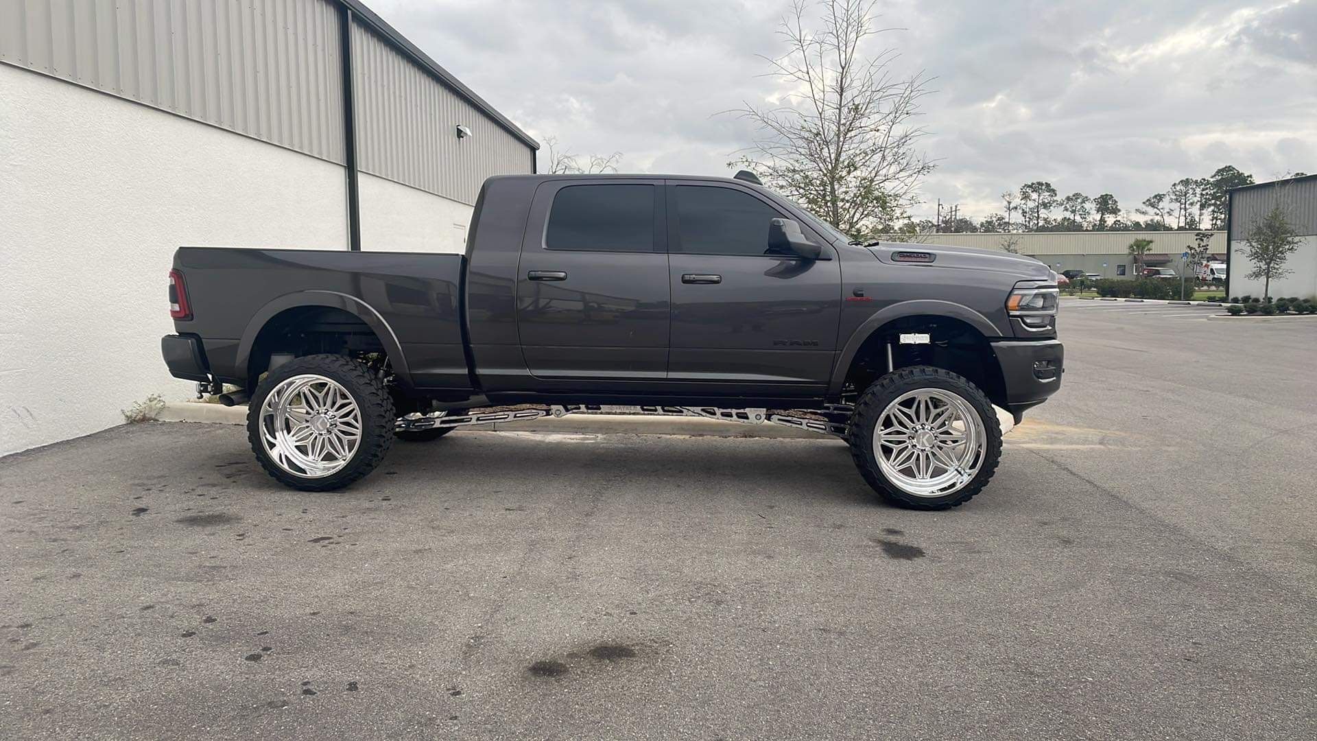 A gray truck is parked in a parking lot in front of a building.